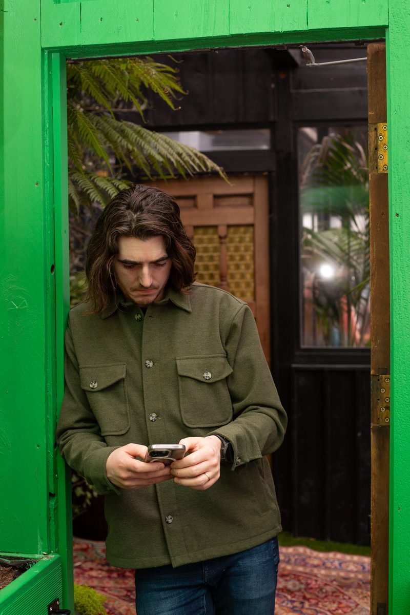 Ben Ó Mathúin leaning against a wall on his phone